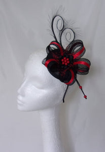 black and red cocktail fascinator hat on black and bright red on a round sinamay base with two black curl feathers at the top a bow loop in black sinamay with a stripe of red satin ribbon and a piece pf netting on red and a black satin ribbon ruffle and red pearls 