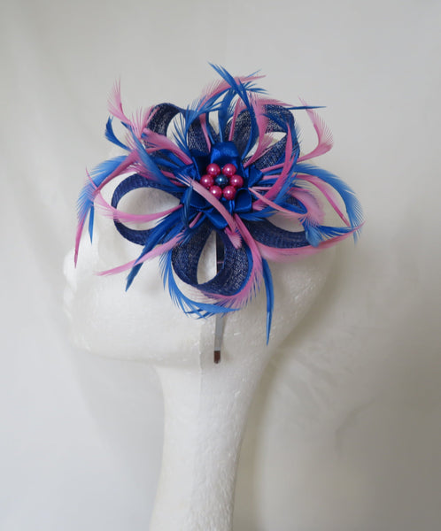 Blue and pink feathered headpiece on a mannequin head against a white background
