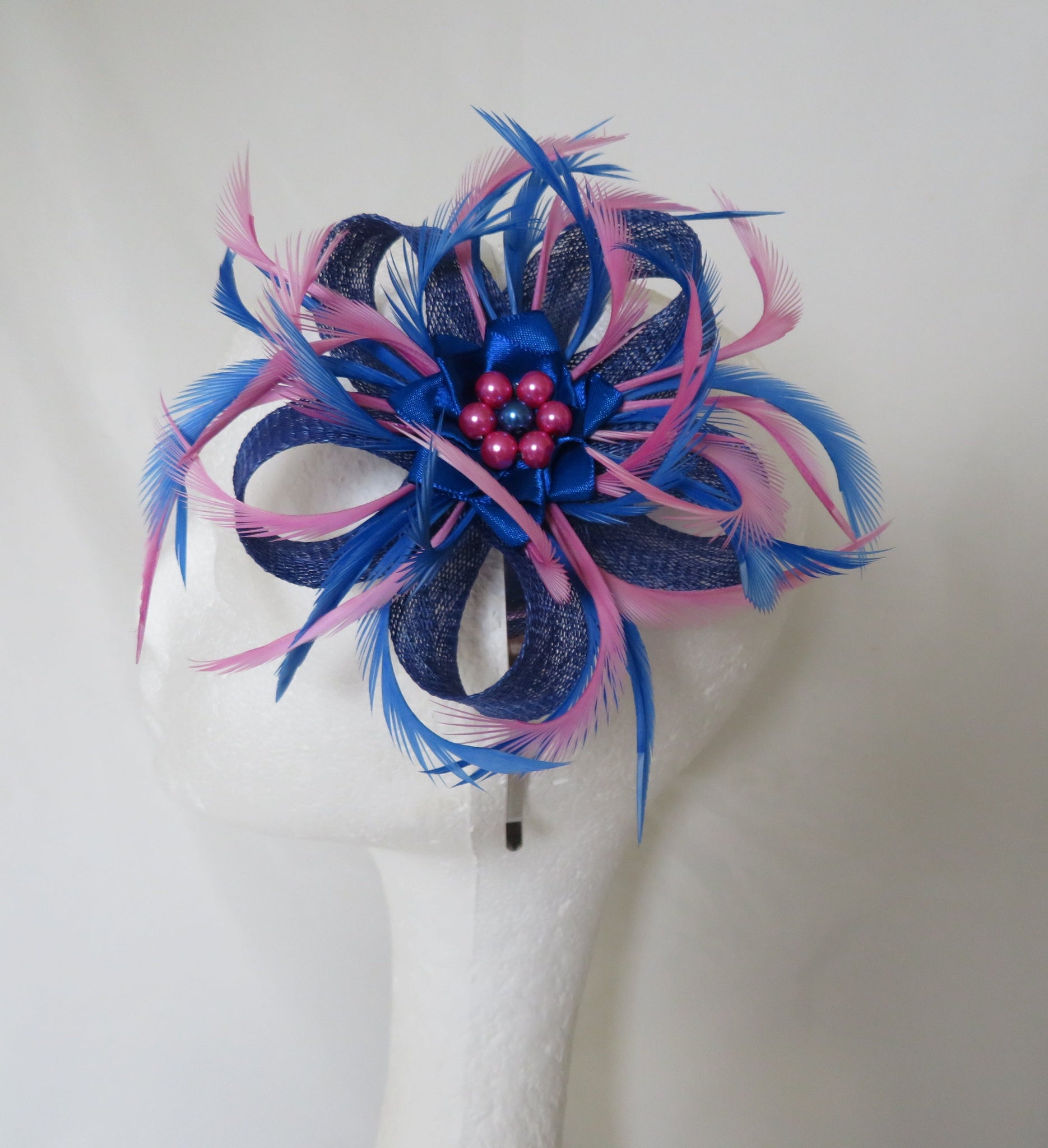 Blue and pink feathered hair accessory on a mannequin head against a white background