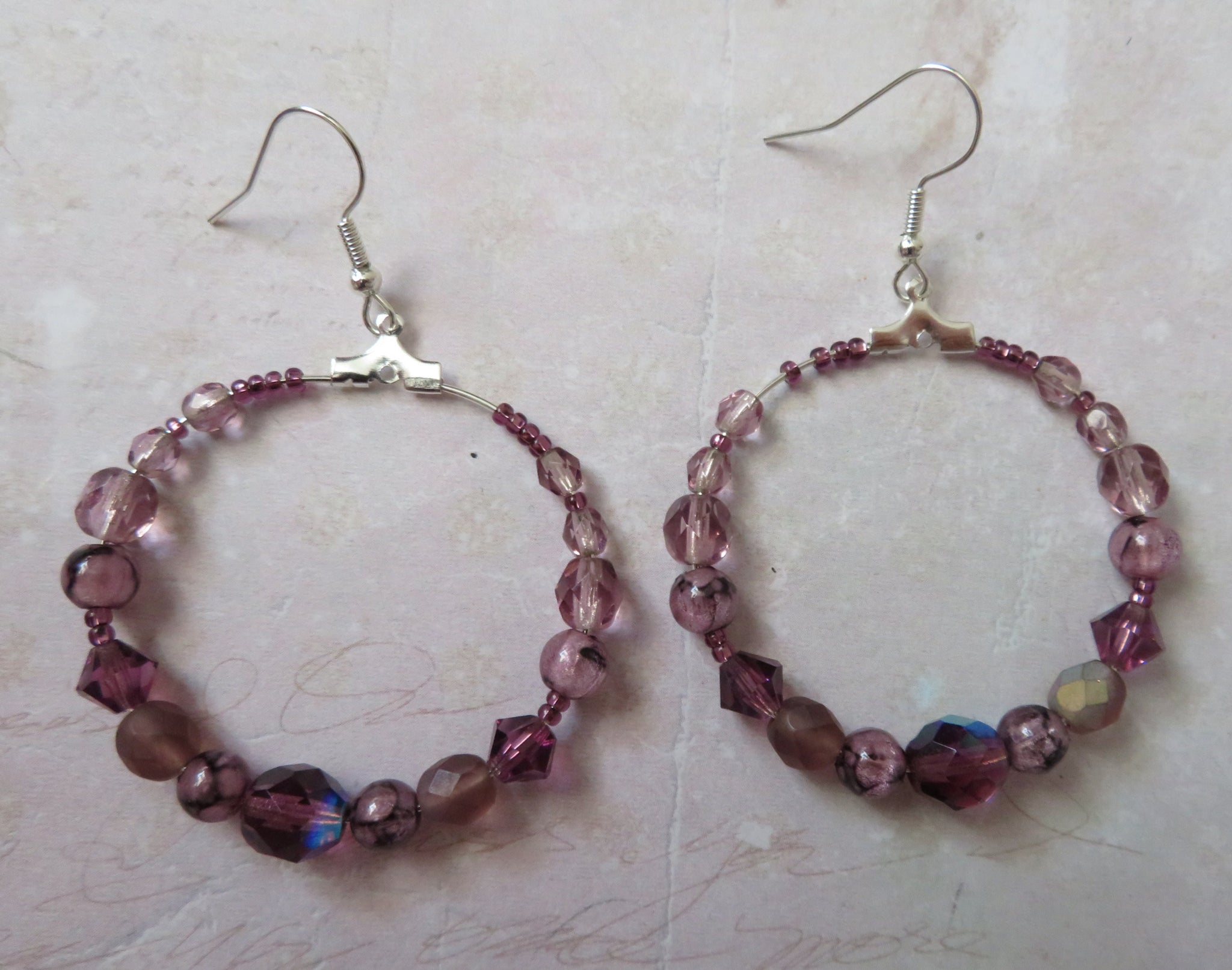 Pair of beaded hoop earrings on a textured surface