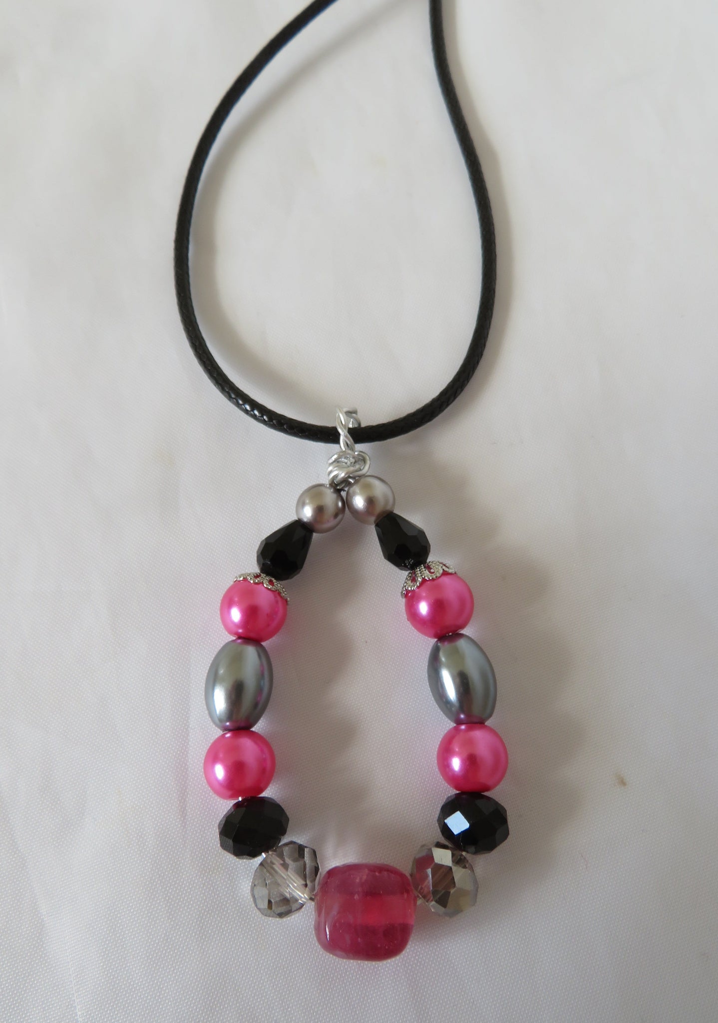Beaded necklace with pink, black, and silver beads on a white background