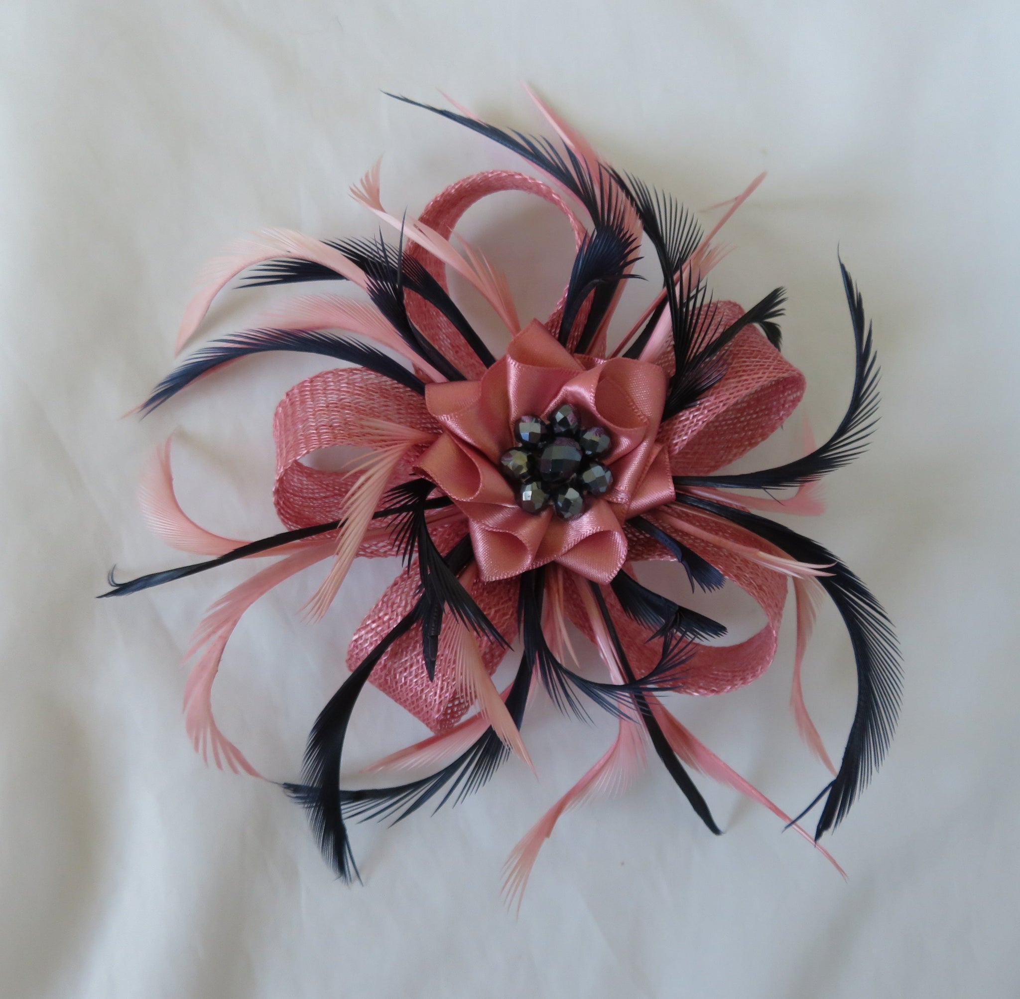 Pink and black feathered hair accessory on a white background