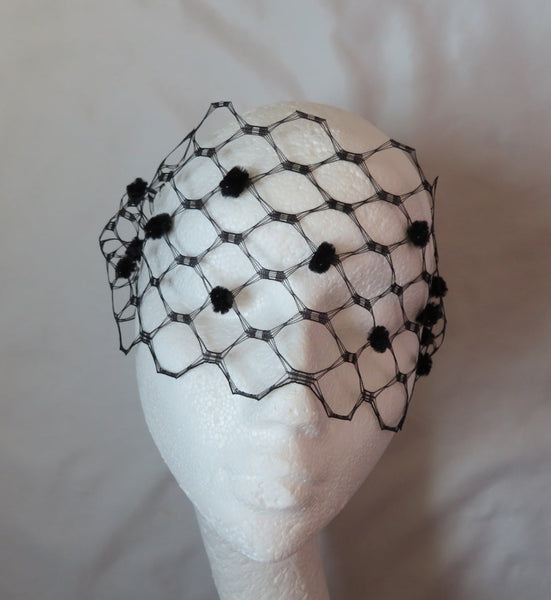 a soft black veil for a bride costume or party in a vintage waffle weave veiling which has large holes about the size of a 50 pence very dramatic fabric narrow so that it just covers the eyes with black chenille fuzzy spots accross the front dotted in a pattern with two black or coloured hair grips or kirbi grips on either end to fix in the hair at the side