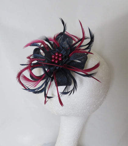 small fascinator with navy blue and burgundy curled feathers with sinamay loops ready made with a clip fixing, navy satin ribbon ruffle and burgundy pearls available to order on a headband also