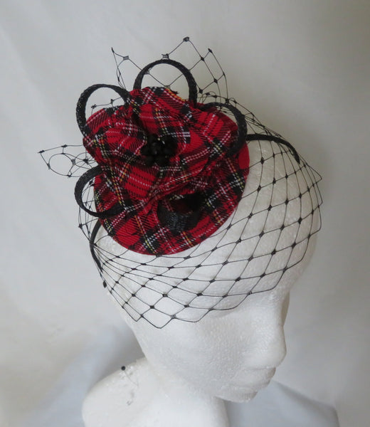Red and black plaid hat with a black netting on a mannequin head against a white background