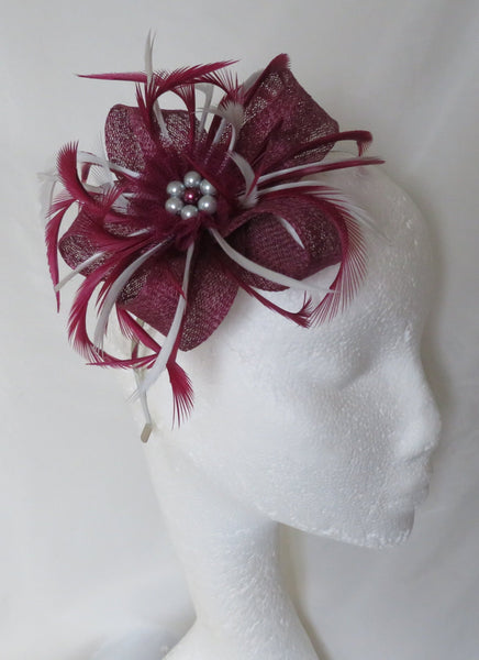 Maroon feathered headpiece on a mannequin head against a white background