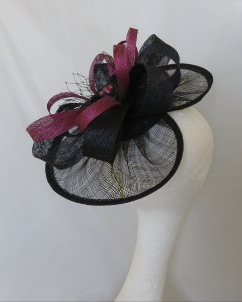 Black and pink decorative hair clip on a mannequin head against a white background