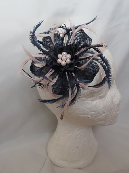 Navy blue and pink feathered hair accessory on a mannequin head against a white curtain.