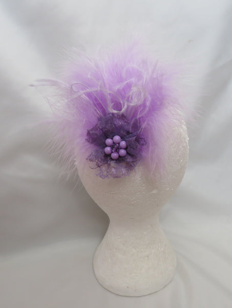 Purple feathered hair accessory on a mannequin head against a white background