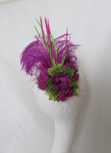 The 'Portia' is made with an amethyst floppy ostrich feather, raspberry magenta pink &amp; lime green biot feathers in a plume. Decorated with a posy cluster of organza &amp; satin pistachio green hibiscus flowers and amethyst delphinium flowers with lime leaves and lime crystal in the centre.