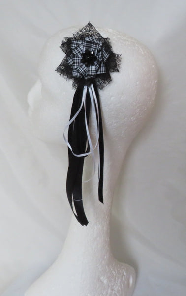A black and silver beaded headband with long black and white ribbon tails, displayed on a white styrofoam mannequin head against a draped white fabric backdrop.
