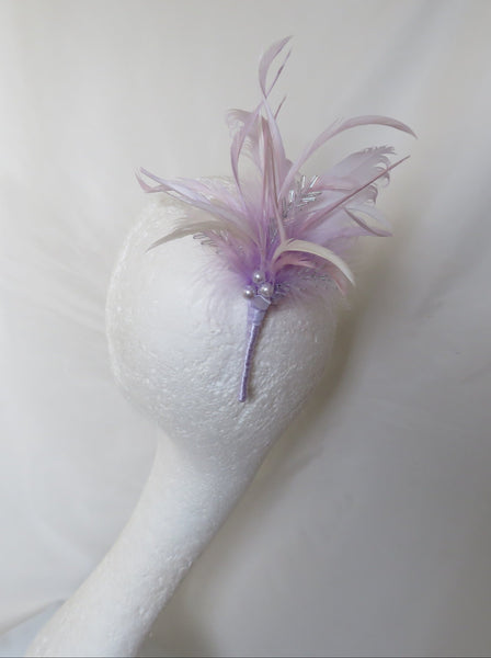 A lavender feather fascinator with small pearl-like beads, displayed on a white styrofoam mannequin head against a draped white fabric background.