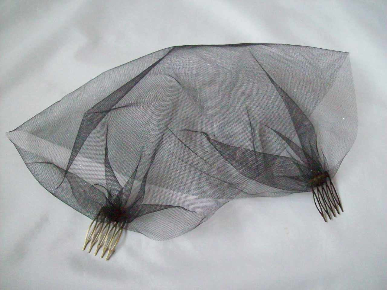 a soft and sheer looking black veil for a bride in a soft tulle netting fabric wider so that it covers the face with small silver or antique bronze metal combs on either end to fix in the hair at the side