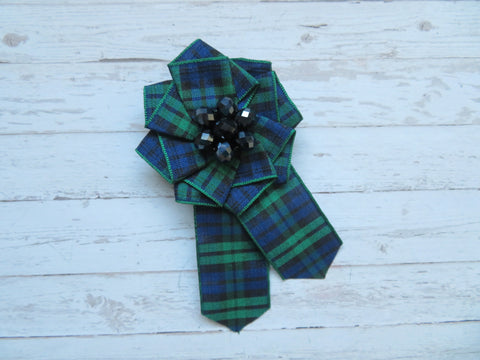 small ribbon ruffle cockade rosette in Black watch tartan which is black, navy royal blue and dark green with a round flower shape of navy blue metallic crystal beads in the centre fixed with a brooch pin