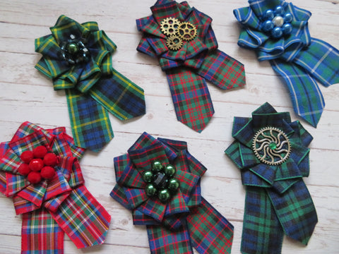 tartan ribbon brooch in a wide range of clan tartan patterns a ruffle cockade design with pointed trails and a choice of pearls or celtic buttons as an embellishment, with a roll bar brooch pin at the back small and perfect for a wedding or adding to a hat or costume