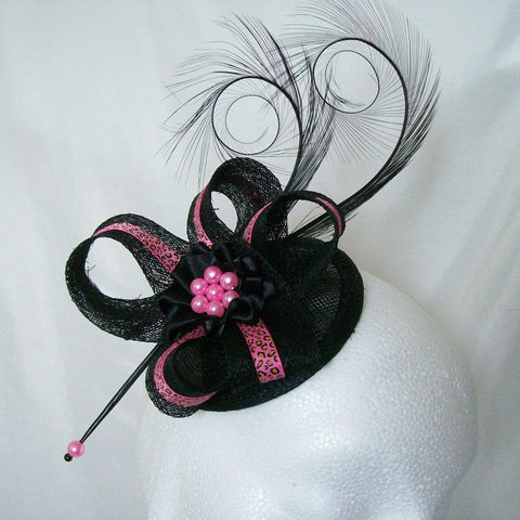 black fascinator on a small round base with long black curl feathers and sinamay loops with hot fuchsia pink leopardprint ribbon on the top with a black satin ribbon ruffle and fuchsia pearls worn on a headband comb or clips