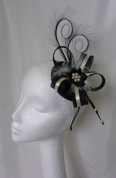 black and ivory cream fascinator with a small round sinamay base, long black curl feathers sinamay loops with a cream narrow satin ribbon stripe overlaid with fluff feathers under a black satin ribbon ruffle and cream pearls fixed with a headband comb or clips